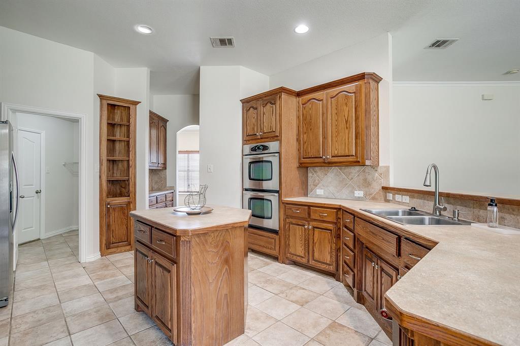 209 Cooperstown Drive Springtown, TX 76082 - Photo 15 of 40 Kitchen with brown cabinetry, light countertops, a center island, arched walkways, and recessed lighting