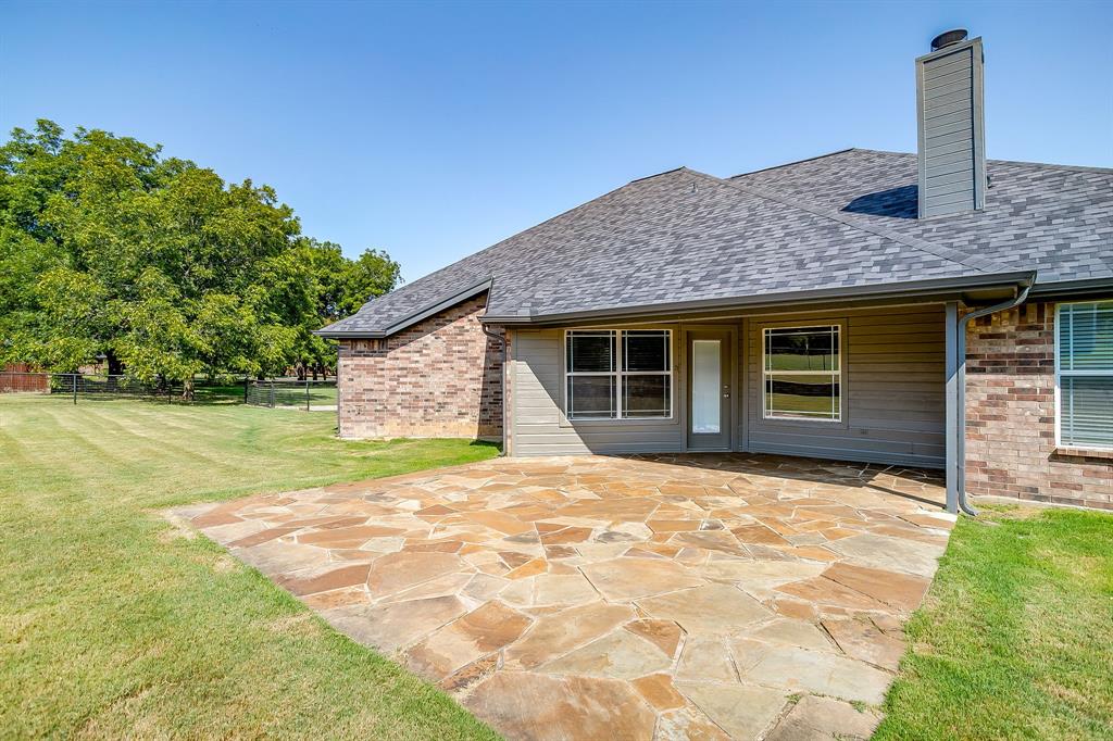 209 Cooperstown Drive Springtown, TX 76082 - Photo 34 of 40 Back of property with roof with shingles, a chimney, a patio area, and brick siding