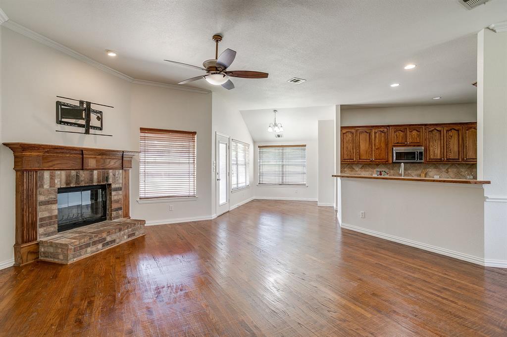 209 Cooperstown Drive Springtown, TX 76082 - Photo 9 of 40 Unfurnished living room featuring a brick fireplace, dark wood finished floors, ceiling fan, recessed lighting, and a chandelier