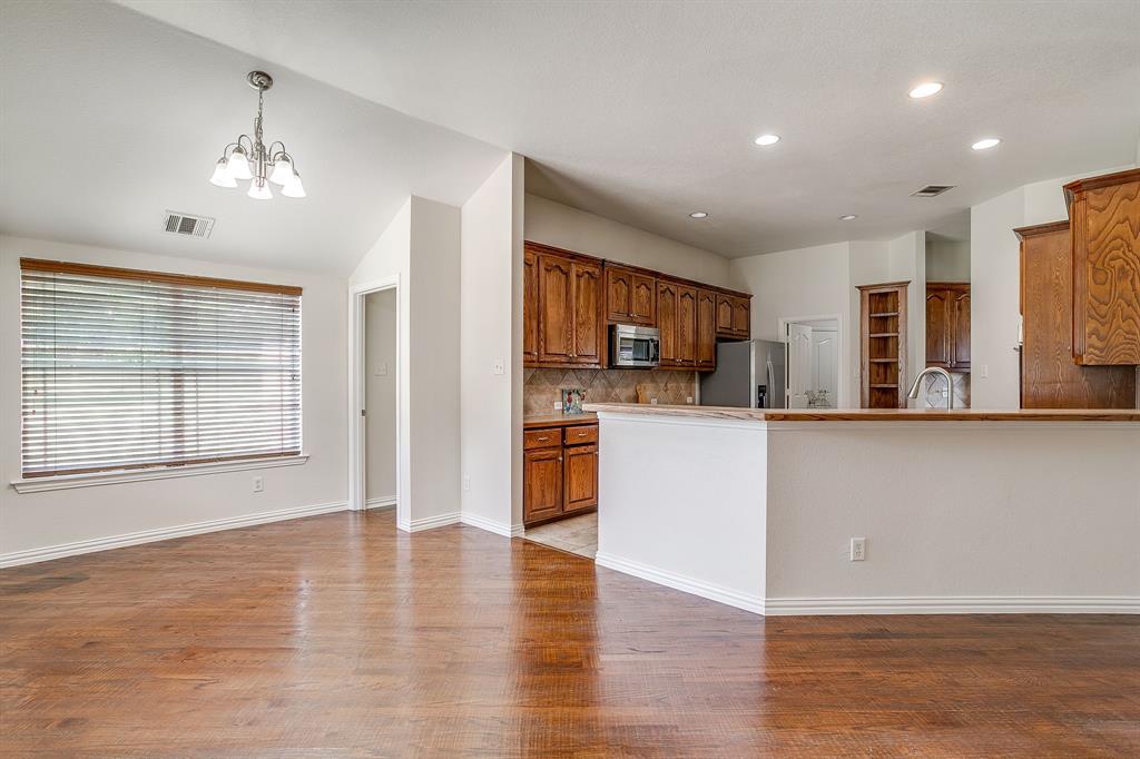 209 Cooperstown Drive Springtown, TX 76082 - Photo 10 of 40 Kitchen with brown cabinets, backsplash, a chandelier, light wood-type flooring, and decorative light fixtures