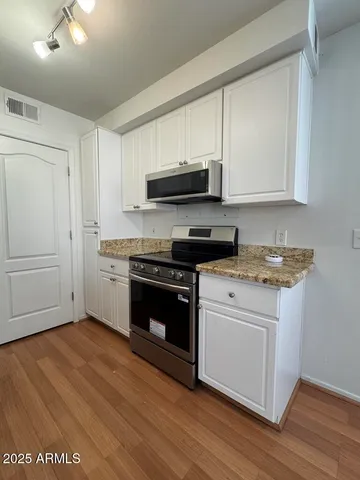 a kitchen with stainless steel appliances granite countertop a stove a sink and a microwave