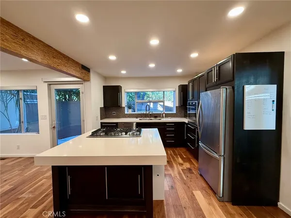 a kitchen with kitchen island a counter top space a refrigerator and a sink