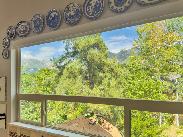 2863 Fallentine Road Sandy, UT 84093 - Photo 11 of 48 Expansive picture window framing a mountainous landscape with abundant mature trees and verdant foliage