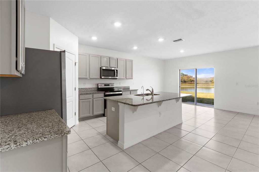 2651 Grandbury Grove Road Lakeland, FL 33811 - Photo 7 of 41 a kitchen with stainless steel appliances kitchen island granite countertop a sink and cabinets