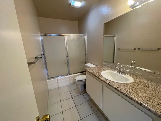 a bathroom with a granite countertop sink a toilet a mirror and shower