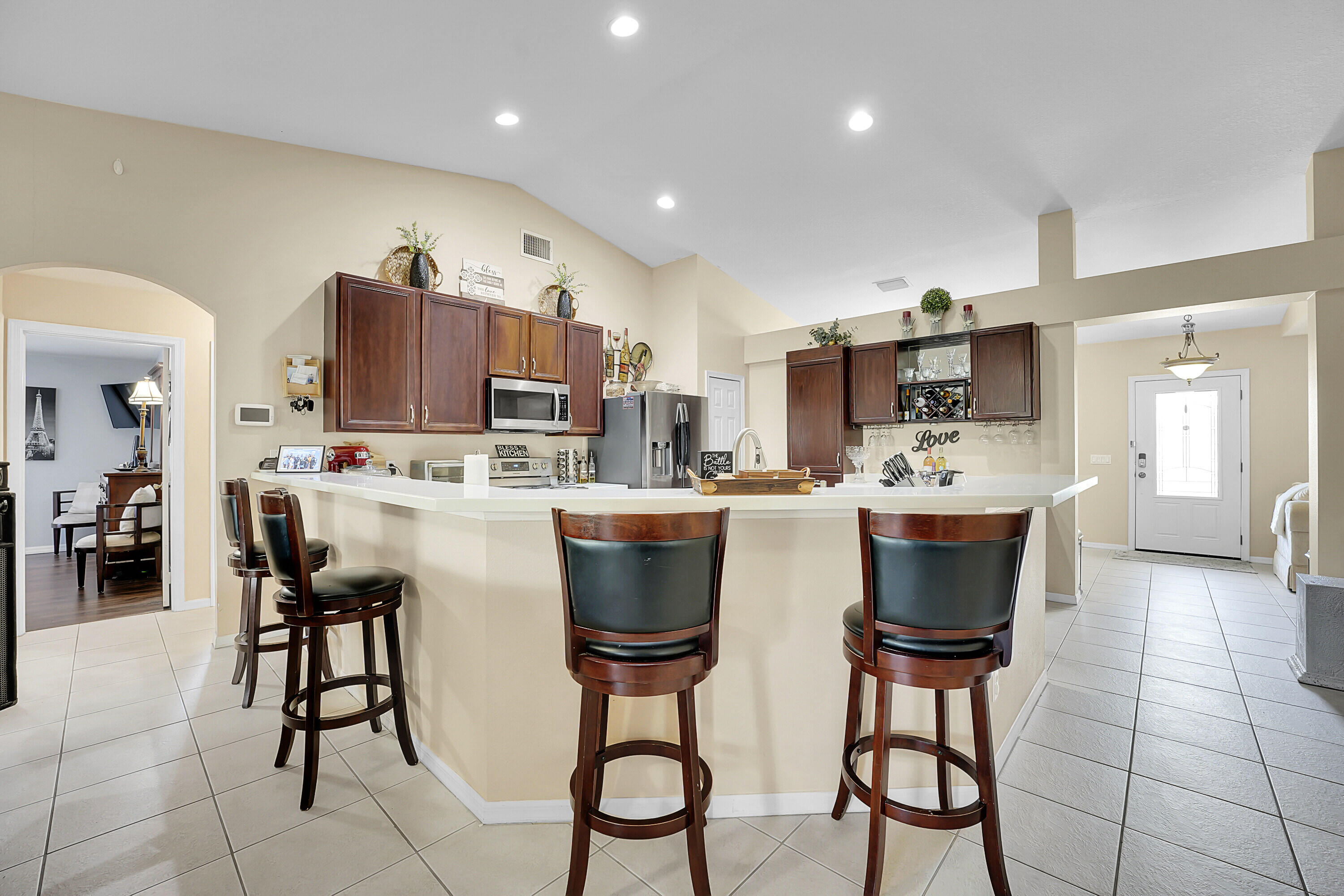 a kitchen with stainless steel appliances kitchen island granite countertop a dining table chairs and a refrigerator