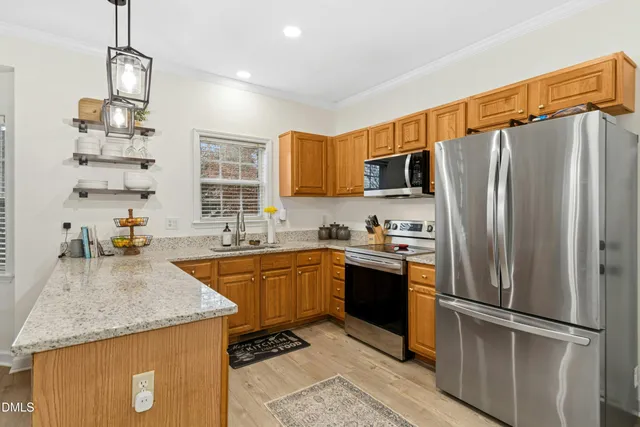 a kitchen with stainless steel appliances granite countertop a refrigerator a sink dishwasher a stove with wooden floor and cabinets