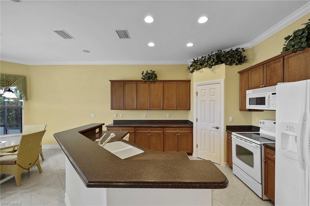 6921 Bent Grass Drive Naples, FL 34113 - Photo 12 of 48 a kitchen with kitchen island a stove a sink a refrigerator and chairs