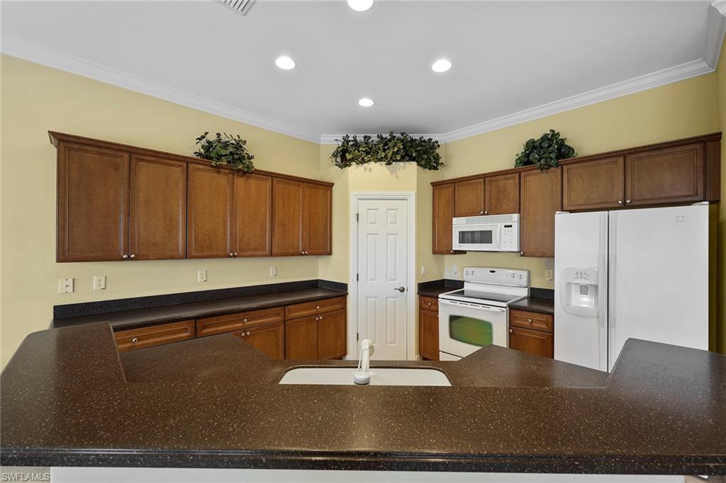 6921 Bent Grass Drive Naples, FL 34113 - Photo 13 of 48 a kitchen with a refrigerator and a stove top oven