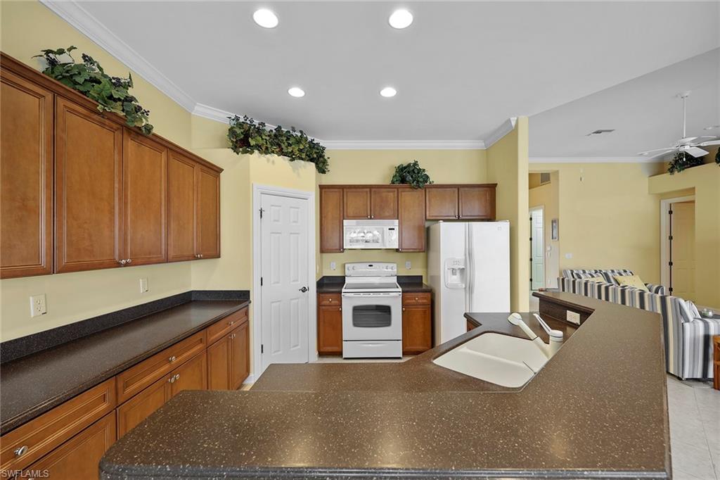 6921 Bent Grass Drive Naples, FL 34113 - Photo 14 of 48 a kitchen with refrigerator and cabinets