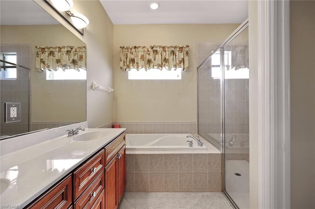 6921 Bent Grass Drive Naples, FL 34113 - Photo 18 of 48 a bathroom with a tub sink and mirror