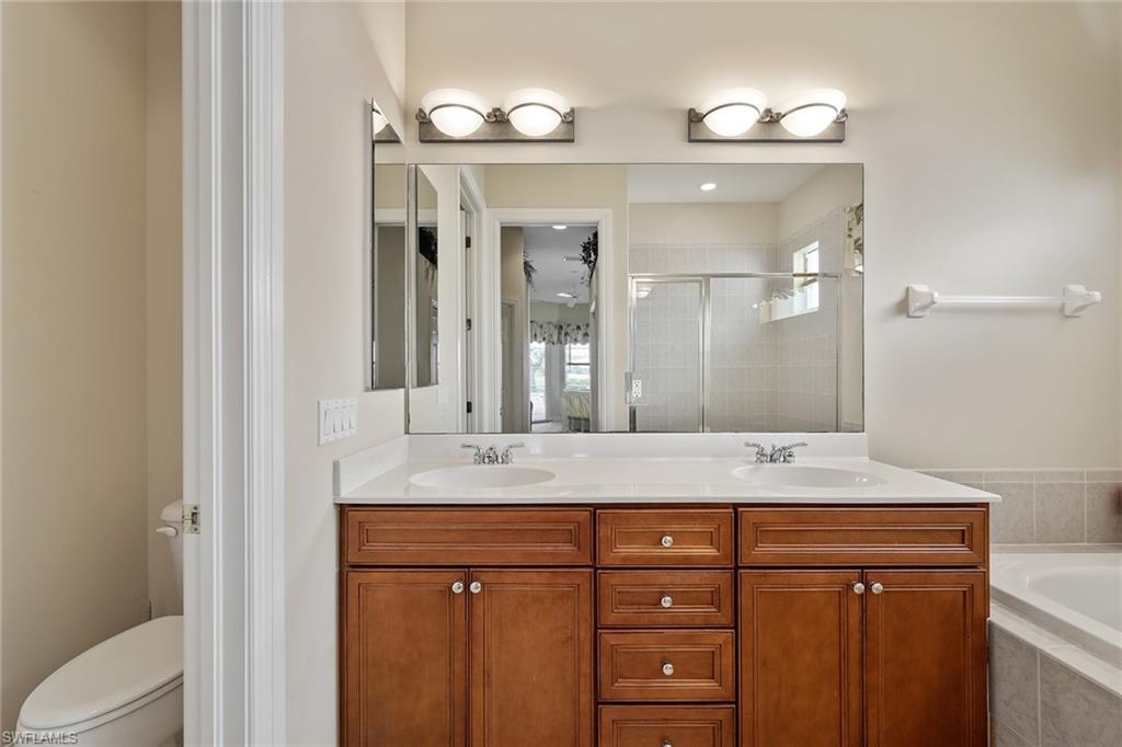 6921 Bent Grass Drive Naples, FL 34113 - Photo 19 of 48 a bathroom with a granite countertop sink a mirror and a vanity