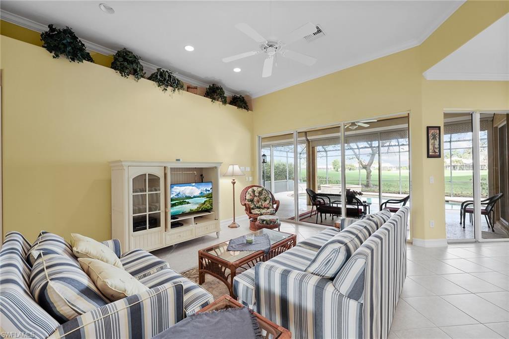 6921 Bent Grass Drive Naples, FL 34113 - Photo 7 of 48 a living room with furniture large windows and a flat screen tv