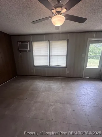 an empty room with windows and chandelier fan