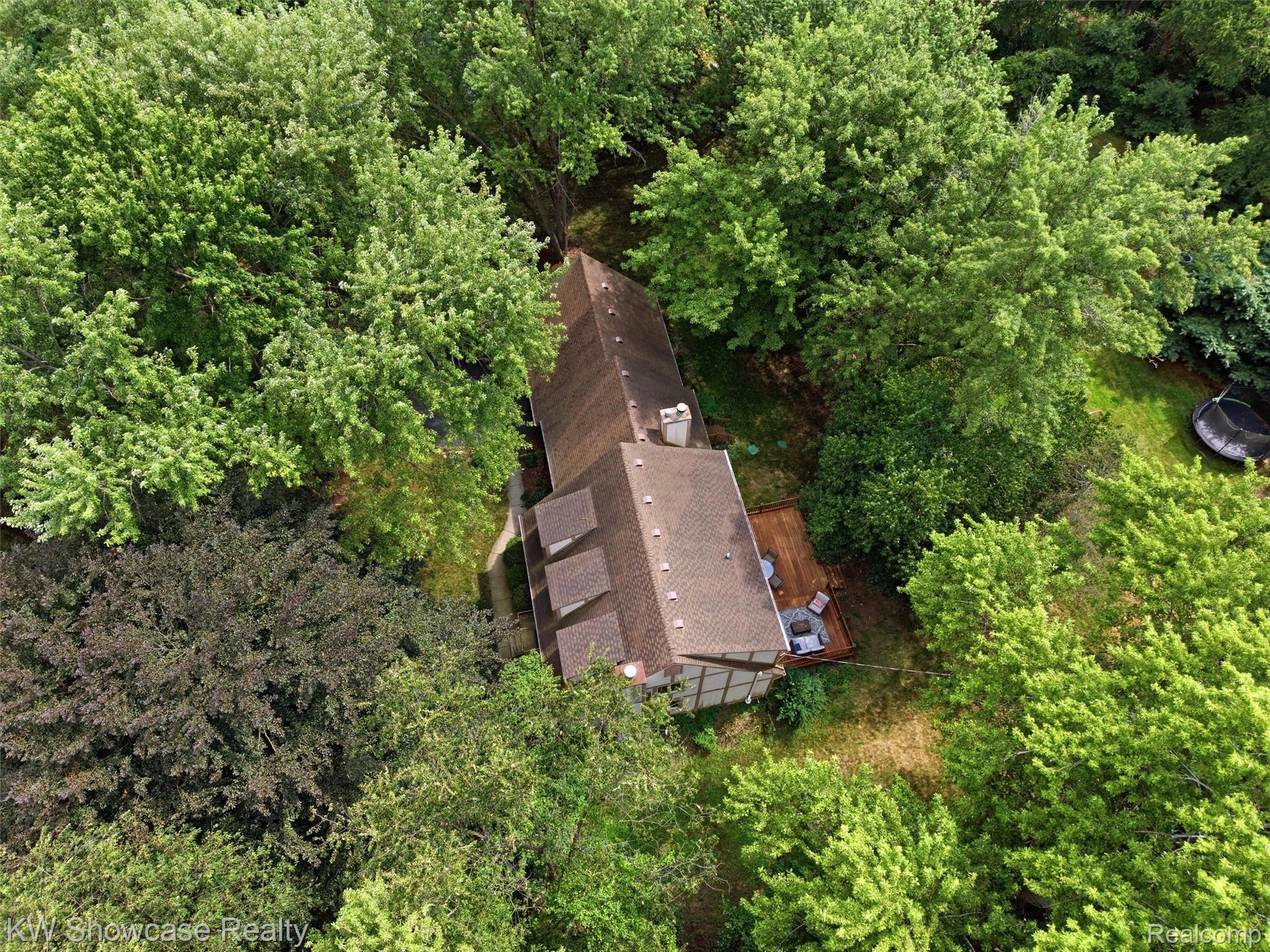 3360 Pleasant Valley Road Brighton, MI 48114 - Photo 55 of 60 Wooded property featuring a multi-level structure with dormer windows, a brown shingle roof, and a visible wooden deck
