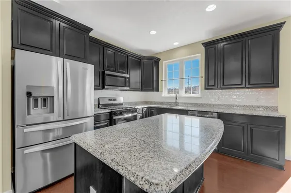 a kitchen with stainless steel appliances granite countertop a refrigerator a sink and wooden cabinets