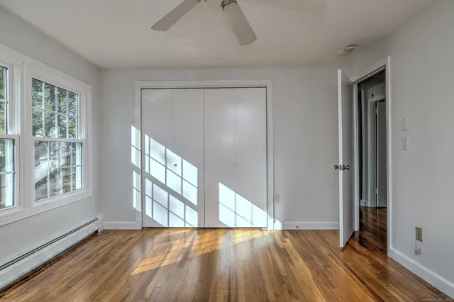 a view of an empty room with wooden floor and a window