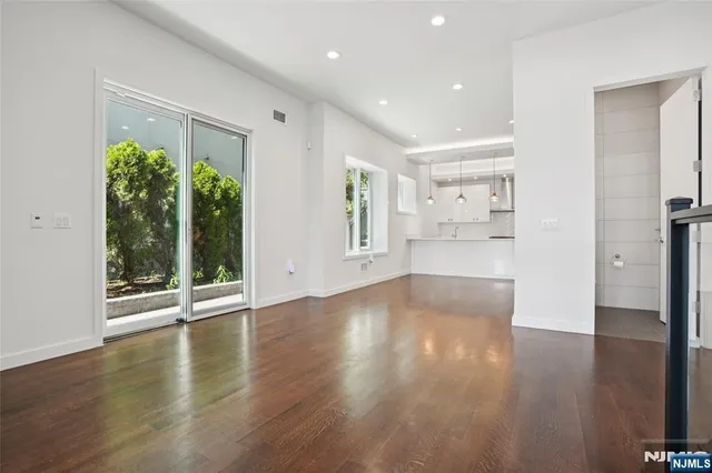 a large white kitchen with a large island oven a sink dishwasher and white cabinets with wooden floor
