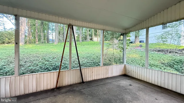 a view of an empty room with wooden floor and large windows