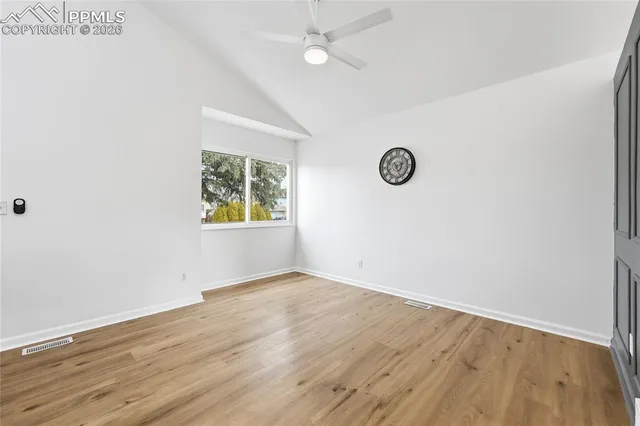 an empty room with wooden floor and fan