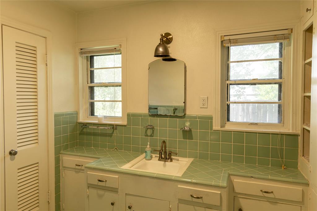 3228 Colcord Avenue Waco, TX 76707 - Photo 20 of 29 Bathroom vanity featuring an integrated sink, dual windows, and built-in storage cabinetry