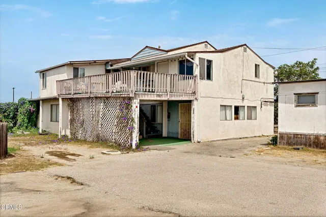 a view of a white house with a large space next to a road