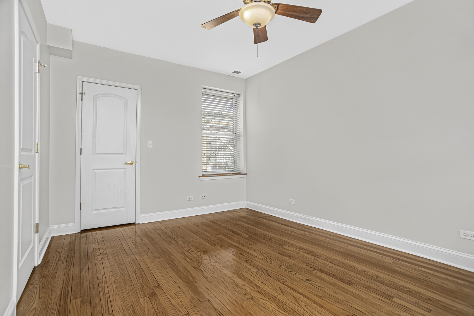 1210 West Roscoe Street, Unit 1 Chicago, IL 60657 - Photo 14 of 20 an empty room with wooden floor chandelier fan and windows