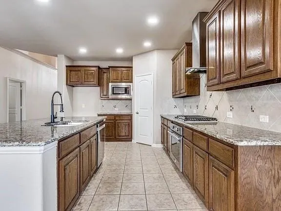 a large kitchen with stainless steel appliances granite countertop a sink stove and refrigerator