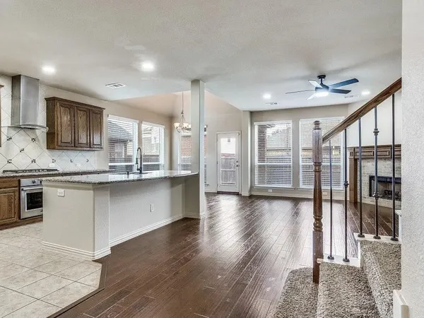 a large kitchen with a center island wooden floor stainless steel appliances and a window