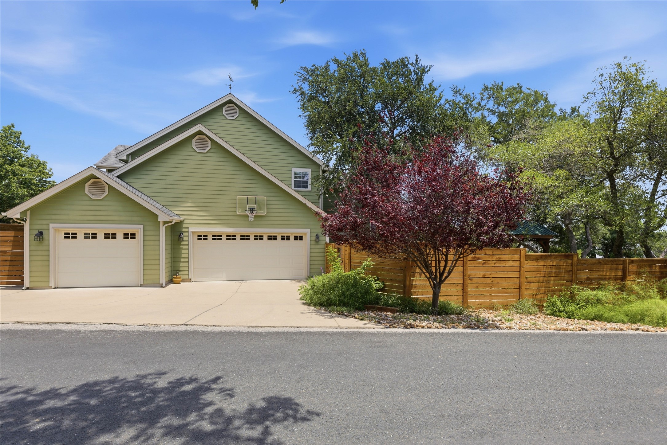 1204 Orlando Road Austin, TX 78733 - Photo 22 of 40 A classic green-sided residence presents two distinct garage entrances, complemented by a sturdy wood fence.