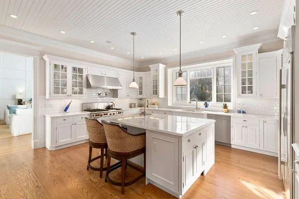 a large kitchen with kitchen island granite countertop lots of white cabinets appliances and a dining table