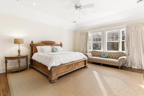 a bedroom with a bed couch and windows