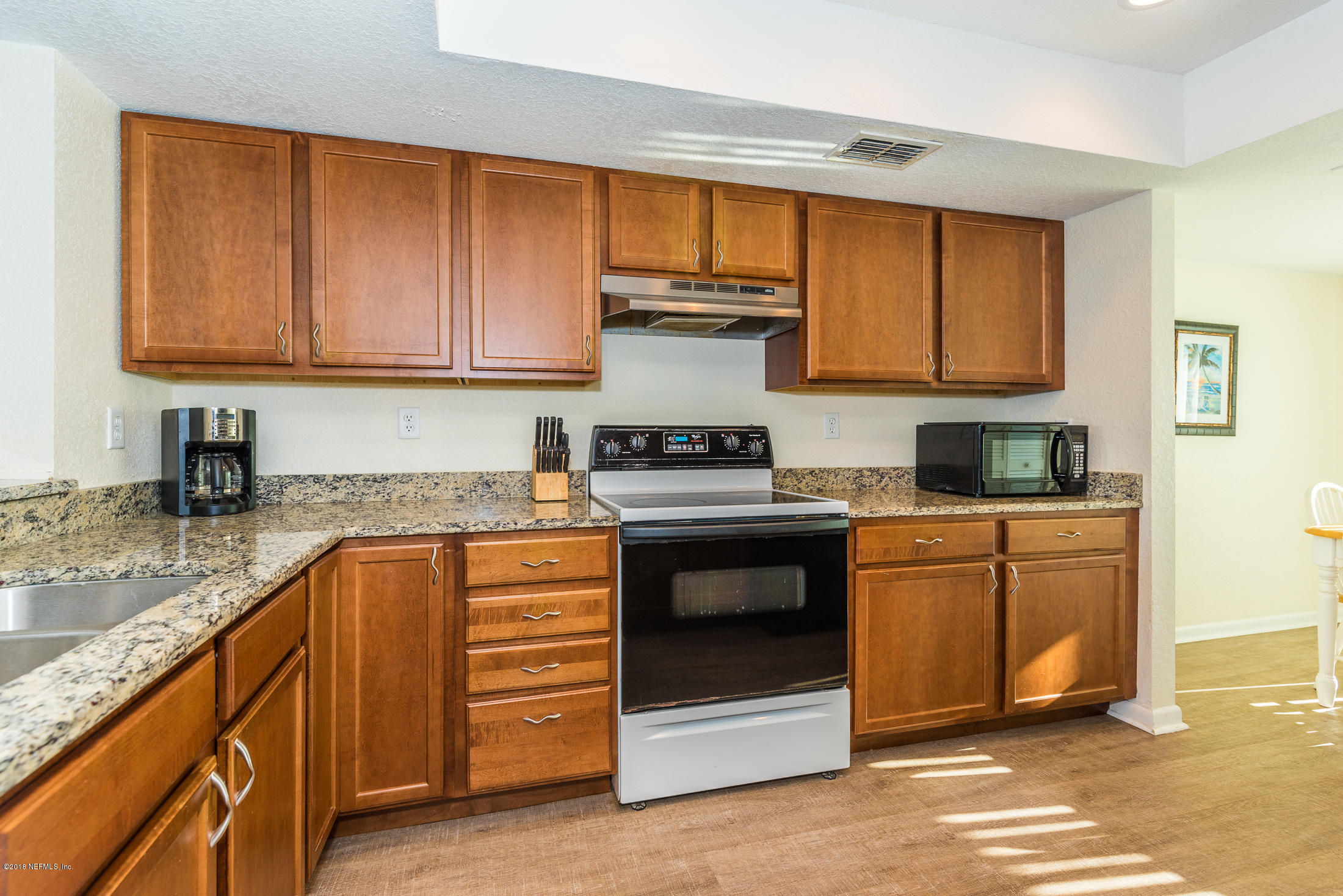 890 A1A Beach Boulevard, Unit 50 St. Augustine, FL 32080 - Photo 24 of 71 a kitchen with granite countertop wooden cabinets and a stove top oven