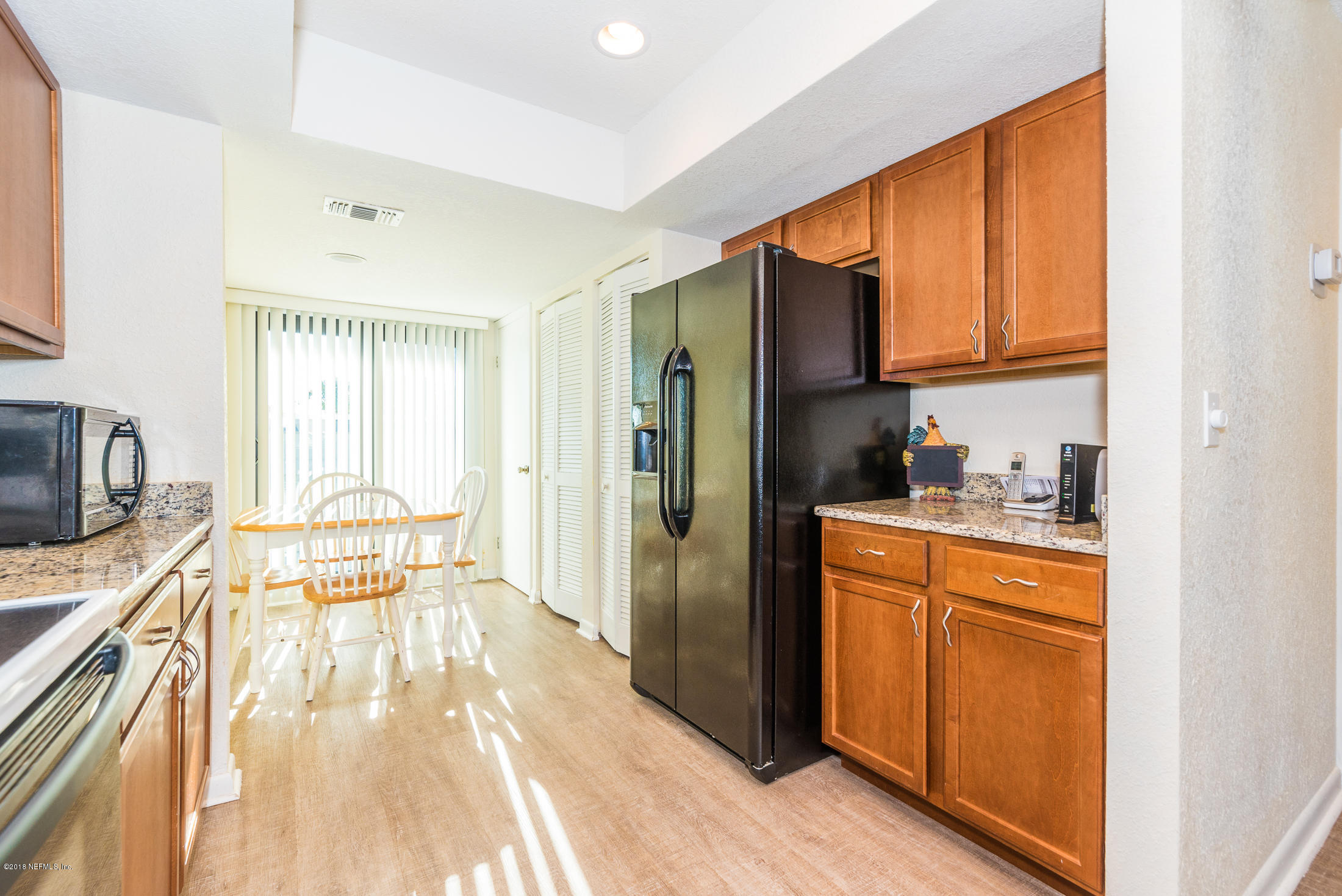 890 A1A Beach Boulevard, Unit 50 St. Augustine, FL 32080 - Photo 26 of 71 a kitchen with stainless steel appliances granite countertop a refrigerator a stove a sink dishwasher and wooden cabinets with wooden floor
