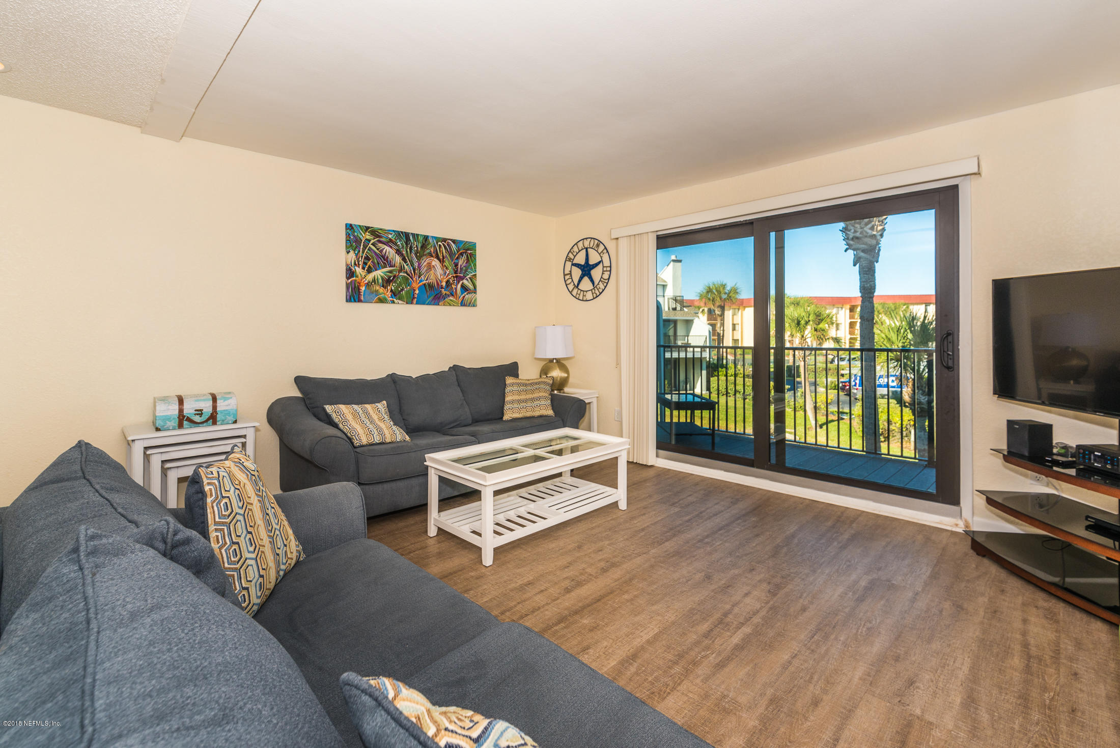 890 A1A Beach Boulevard, Unit 50 St. Augustine, FL 32080 - Photo 33 of 71 a living room with furniture a flat screen tv and a floor to ceiling window