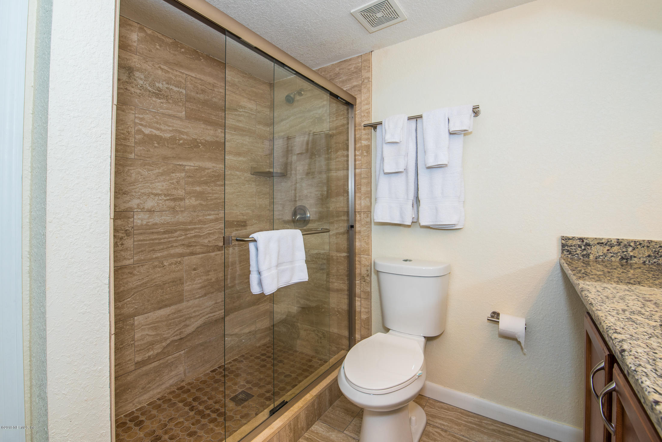890 A1A Beach Boulevard, Unit 50 St. Augustine, FL 32080 - Photo 48 of 71 a bathroom with a granite countertop toilet a sink and a shower