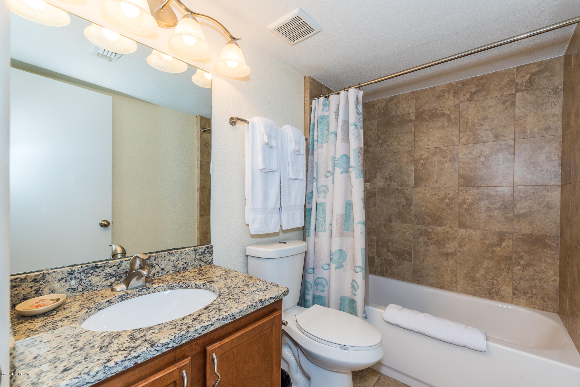 890 A1A Beach Boulevard, Unit 50 St. Augustine, FL 32080 - Photo 8 of 71 a bathroom with a granite countertop sink a toilet a mirror and shower