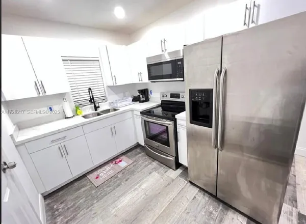 a kitchen with a sink a refrigerator a window and cabinets
