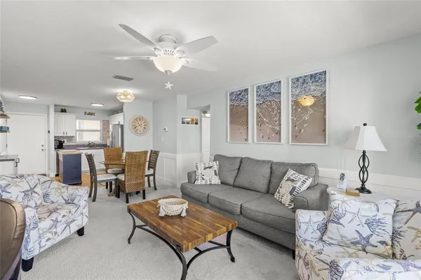 a living room with furniture kitchen view and a chandelier