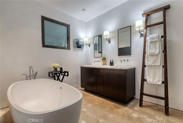 a en suite bathroom with a double vanity sink a mirror and a bathtub