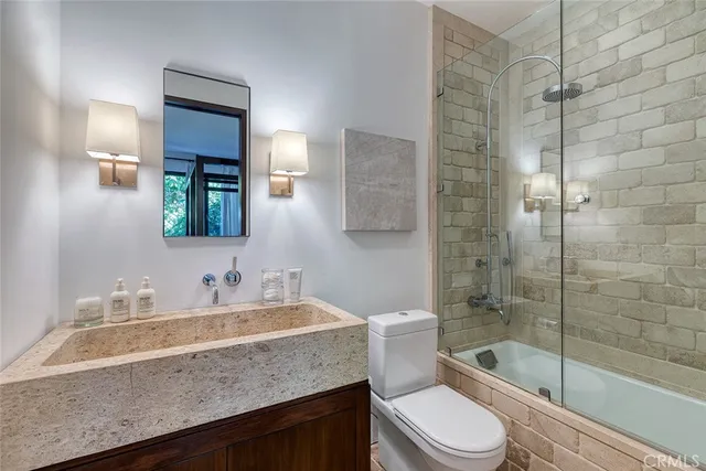 a bathroom with a granite countertop sink a toilet a mirror and shower