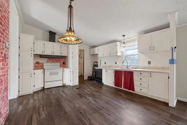 a kitchen with stainless steel appliances granite countertop a stove a refrigerator and white cabinets with wooden floors