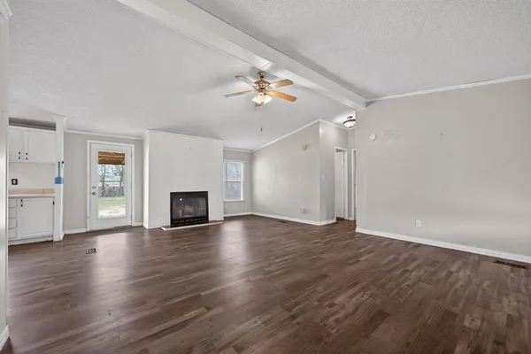 an empty room with wooden floor fireplace and ceiling fan