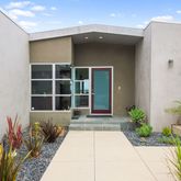 a front view of a house with a large window and potted plants