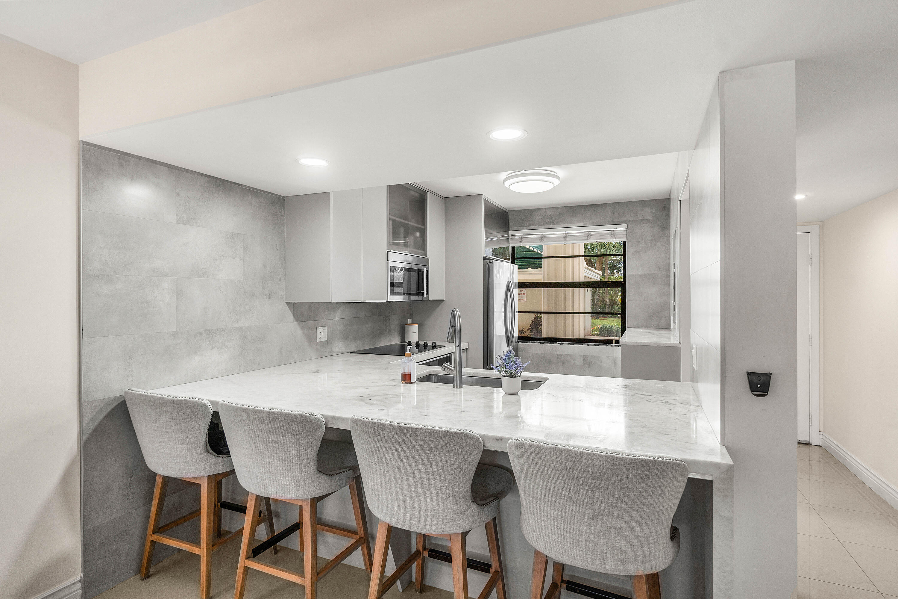 6049 Balboa Circle, Unit 103 Boca Raton, FL 33433 - Photo 5 of 26 a kitchen with kitchen island cabinets dining table and chairs