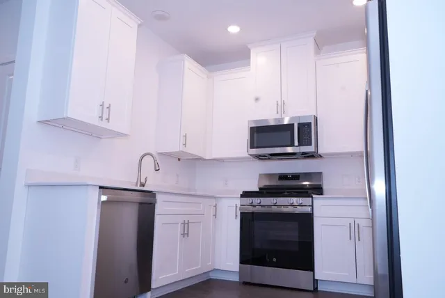 a kitchen with stainless steel appliances a stove a microwave and white cabinets