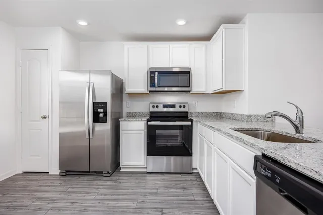 a kitchen with granite countertop a refrigerator and a sink