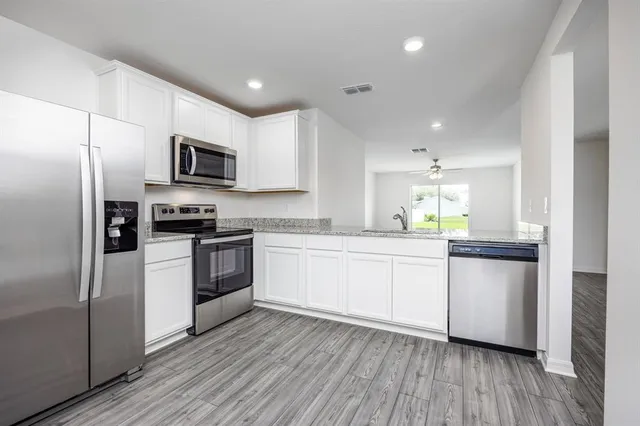 a kitchen with white cabinets stainless steel appliances and wooden floor