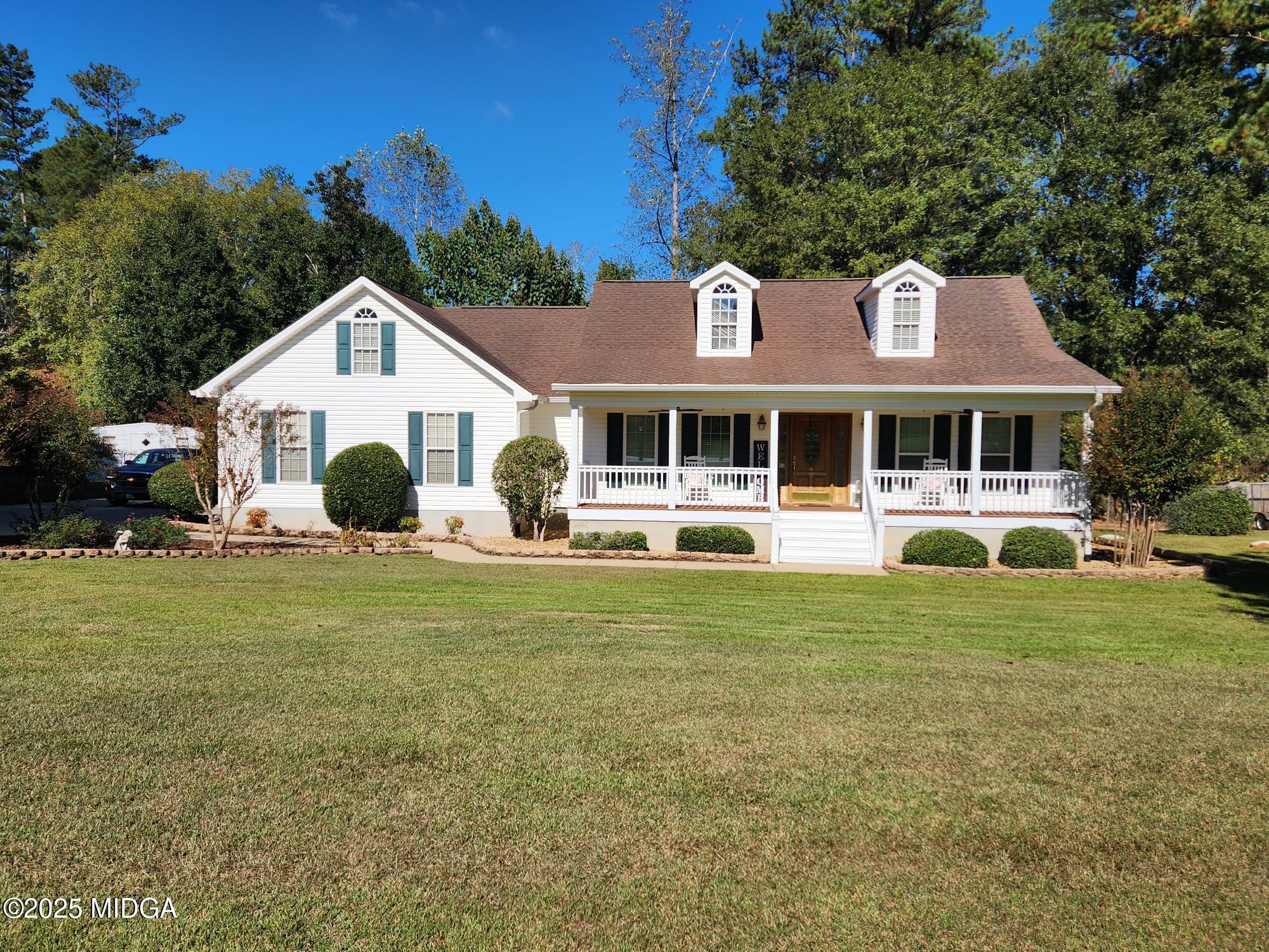 a front view of a house with garden and trees