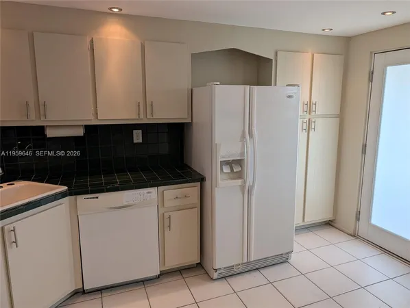 a kitchen with white cabinets and refrigerator